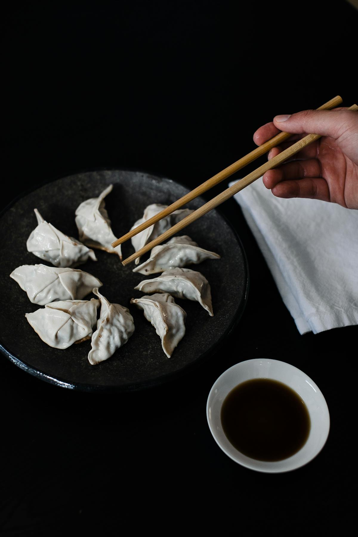 Crop person with chopsticks and gyoza