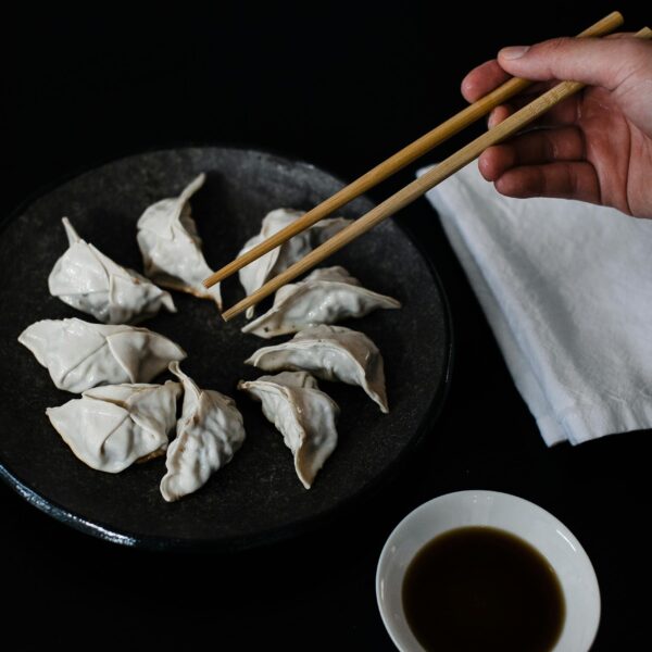 Crop person with chopsticks and gyoza